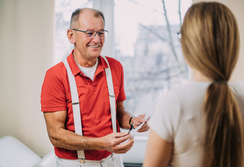 Ein freundlicher Arzt berät eine Patientin in einer Praxis für Ganzheitliche Medizin, angenehme Atmosphäre mit Tageslicht und individueller Betreuung.